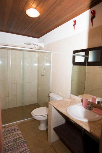 a bathroom with a toilet and a sink and a mirror at Casa Andrea in Praia do Forte