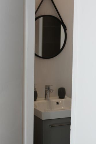 une salle de bain avec un lavabo et un miroir au mur dans l'établissement Royantine, à Aubagne