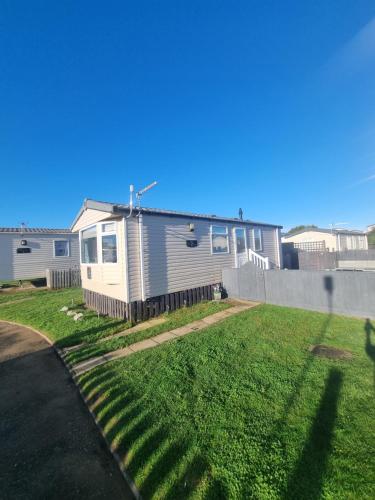 a small house in a yard next to a fence at 1 minute walk to the beach here! 37 Unity Beach Brightholme Brean sleeps 6 Pet friendly Pets stay free in Brean