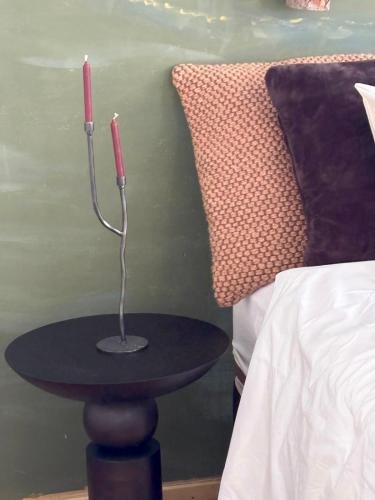 a table with two candles on it next to a bed at Suite Vigia Jardim in Jardim do Mar