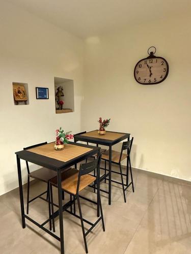 two tables with chairs and a clock on the wall at B&B Arco Trinità in Bari