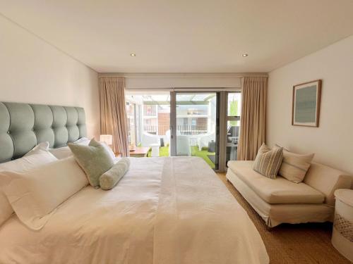 a bedroom with a large white bed and a couch at Kana Vista in Plettenberg Bay