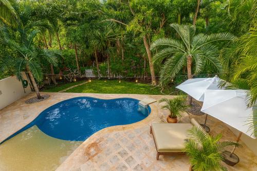 a swimming pool with an umbrella and a table and chairs at 7BR Private Jacuzzi & Pool Villa Sleeps 16 Walk to Beach Lagoon and Golf in Puerto Aventuras