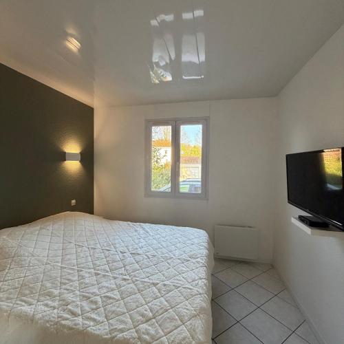 Un dormitorio con una cama y un televisor de pantalla plana. en Maison de vacances 3 étoiles - Sous les Pins, en Ozillac