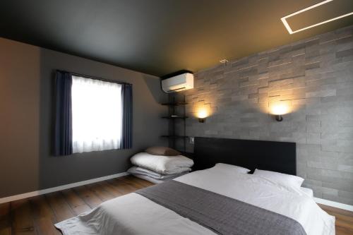 a bedroom with a bed and a brick wall at Casa Stay Kokura 1 - Vacation STAY 18791v in Kitakyushu