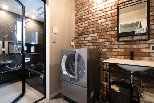 a bathroom with a washer and dryer next to a brick wall at Casa Stay Kokura 1 - Vacation STAY 18791v in Kitakyushu