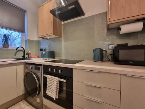 a kitchen with a stove and a sink and a microwave at Brand new modern and stylish 2 bedroom apartment in Sheffield