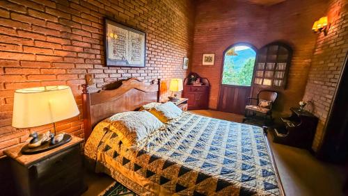 een slaapkamer met een bed en een bakstenen muur bij Estalagem Entardecer da Serra in Monte Verde