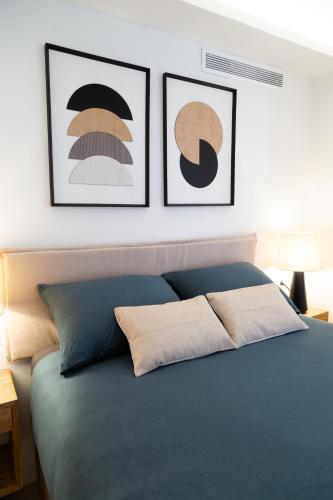 a bedroom with a blue bed with three pictures on the wall at Boutique Apartment with Sun Terrace & Sea Views in Torremolinos