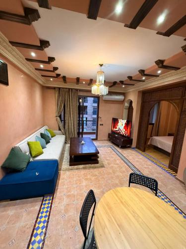een woonkamer met een blauwe bank en een tv bij Appartement pour les séjours in Marrakesh
