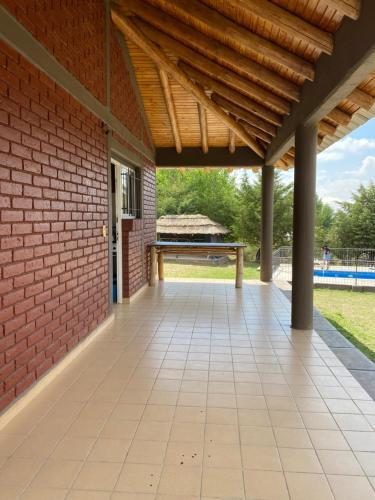 eine Außenterrasse mit einer Ziegelmauer und einem Holzdach in der Unterkunft Cabañas Las Carditas in Mendoza
