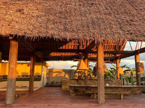 een groot gebouw met een rieten dak en een patio bij Villa Papaya in Jomba