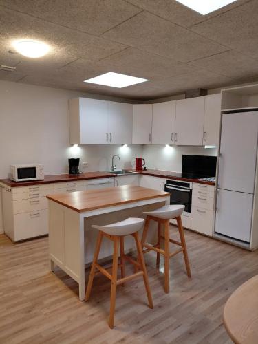 a kitchen with white cabinets and a table and two stools at Apartment in green area in Grindsted