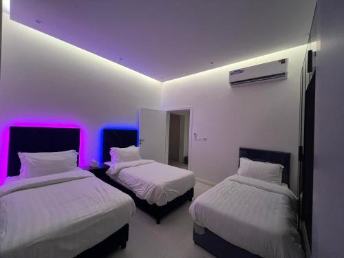 2 Betten in einem Zimmer mit lila Leuchten in der Unterkunft شقة خاصة in Dschidda