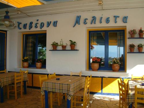 a restaurant with tables and chairs and plants on the wall at Melistas Rooms in Marathias