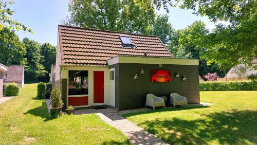 a small green house with two chairs in a yard at Vakantiehuis Toermalijn in Simpelveld