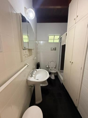 a white bathroom with a toilet and a sink at CASA El CORRALÓN in Las Toninas