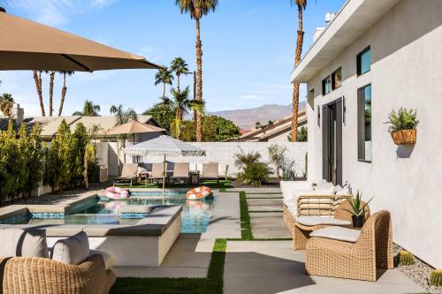 a patio with chairs and a pool with palm trees at Desert Oasis: Pool, Spa, Golf Sim + EV Charger in Bermuda Dunes