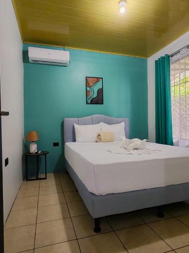 a bedroom with a white bed with a blue wall at Butterfly Apartments La Fortuna in Fortuna