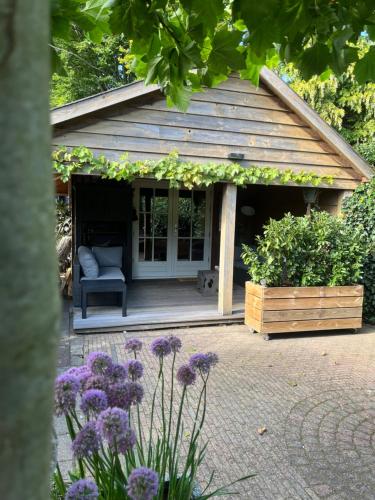 a small house with a chair and flowers at Het Houten Huis in Hierden