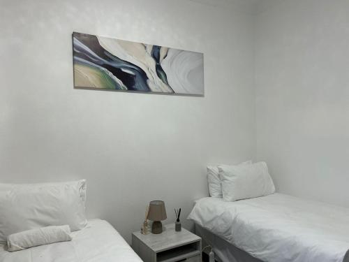 ein Schlafzimmer mit zwei Betten und einem Gemälde an der Wand in der Unterkunft Monkoma Apartments in Mbabane