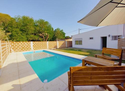 een zwembad met twee banken en een parasol bij Los Fresnitos in Villa Lía