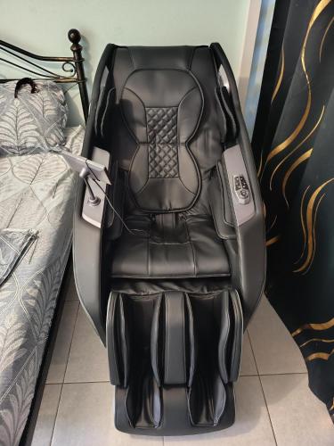 a black gaming chair sitting next to a bed at Loveroom avec siège massant et spa in Cayenne