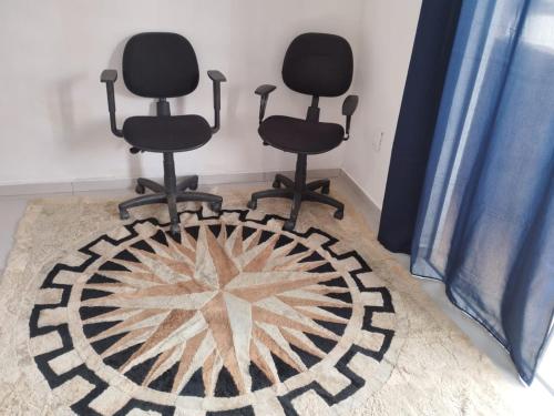 Twee zwarte stoelen staan in een kamer met een vloerkleed. bij Suíte 4 Centro de São Thomé das Letras in São Thomé das Letras