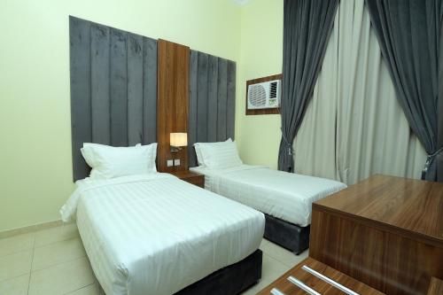 Una habitación de hotel con dos camas y un escritorio. en منازل الحساء للشقق الفندقية, en Al Hofuf