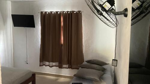 una camera da letto con una finestra con una tenda e cuscini di loft 2 sitio do barrigudinho a Saquarema