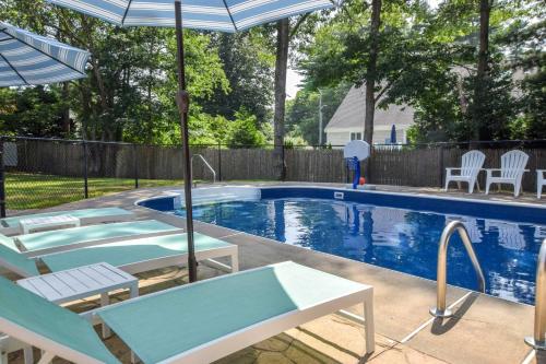 a swimming pool with chairs and an umbrella at Private Saltwater Pool Game Room near Beaches in Barnstable