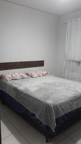 a bed in a white room with a window at Cantinho da paz in Gravatá