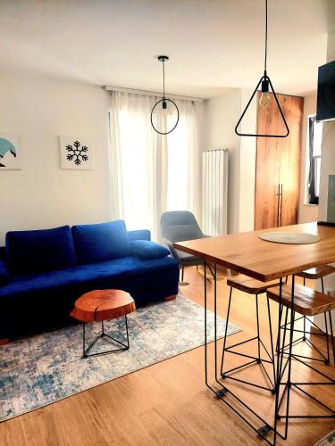 ein Wohnzimmer mit einem blauen Sofa und einem Tisch in der Unterkunft Bianca in Jahorina