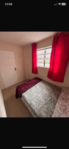 Un dormitorio con una cama y una ventana con cortinas rojas. en Hostel San Pietro, en Santos