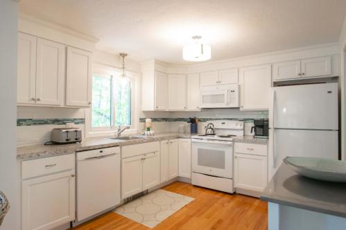 una cocina con armarios blancos y electrodomésticos blancos en 5-Mins to Forest Beach Dog Friendly, en Chatham