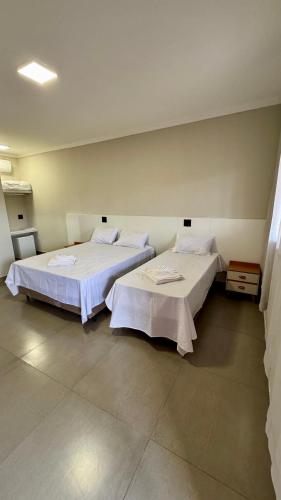 zwei Betten, die in einem Zimmer nebeneinander stehen in der Unterkunft Hotel Tamboril in Barra Bonita
