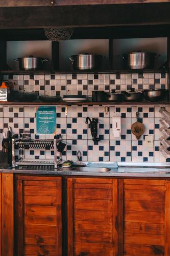 a kitchen counter with pots and pans on a tiled wall at No Worries Pipa in Pipa