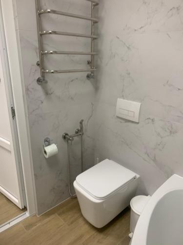 a bathroom with a white toilet and marble walls at Будинок з чаном in Druzhba