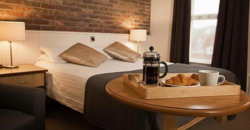 The Terrace Hotel في ماغيرافيلت: غرفة فندق بها سرير وطاولة عليها صينية خبز