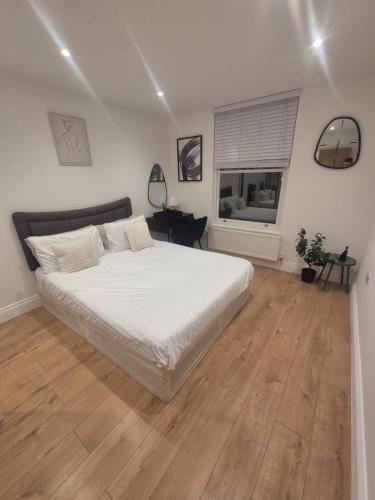 a bedroom with a large white bed and a desk at 2Bed Ground Floor Apartment With Private Garden in London