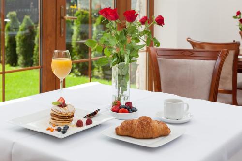 a table with a plate of pancakes and a vase of roses at Boutique Hotel Budzak in Ždiar