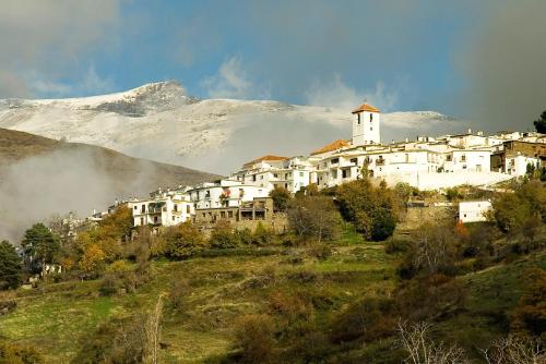una ciudad en una colina con una montaña cubierta de nieve en Capileira Luz de Sierra, en Capileira