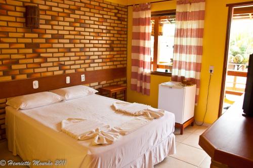 a bedroom with a bed with towels on it at Pousada Pargos in Itaúnas