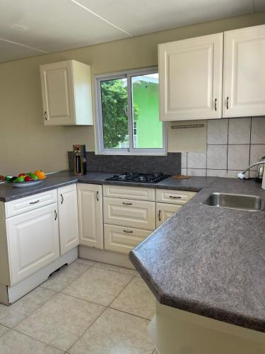 una cucina con mobili bianchi, un lavandino e una finestra di House on the mountain a Willemstad