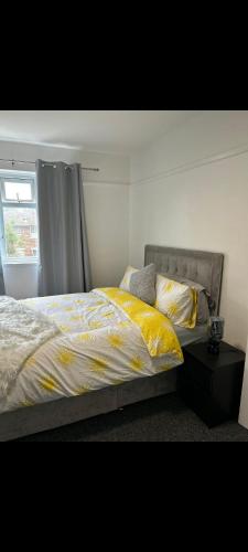 een slaapkamer met een bed met een geel dekbed en een raam bij Grove manor in Streatham Vale