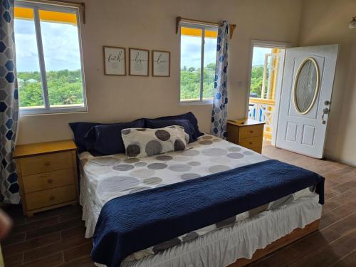 a bedroom with a bed with blue sheets and windows at Cozy Hill Vista in Micoud