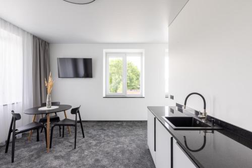 een witte keuken met een tafel en een wastafel bij Varenastay in Varėna