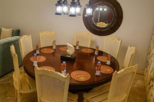 een eettafel met stoelen, een houten tafel en een spiegel bij Liora Inside Al Dana beach Resort in Half Moon Bay