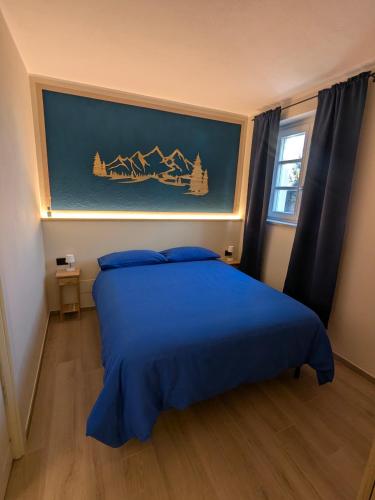 a bedroom with a blue bed with a painting on the wall at Il Boschetto della Valle Maira in Villar San Costanzo