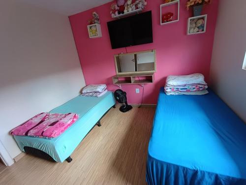Camera con 2 letti e TV su una parete rosa di Sobrado em área tranquila a Caxias do Sul